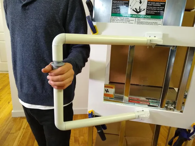 A hand gripping a full-size mocked-up cart handle